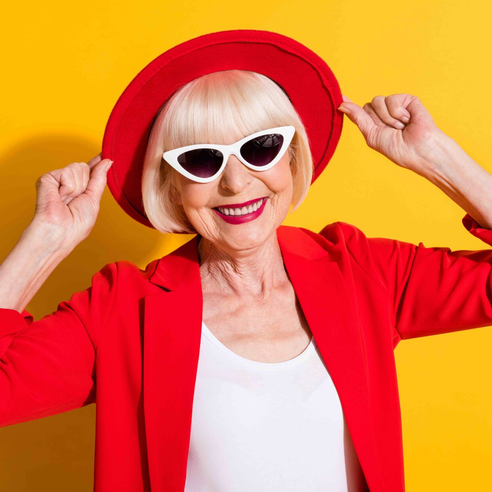 Photo portrait of happy senior lady wearing sunglass red hat smiling in blazer isolated on bright yellow color background